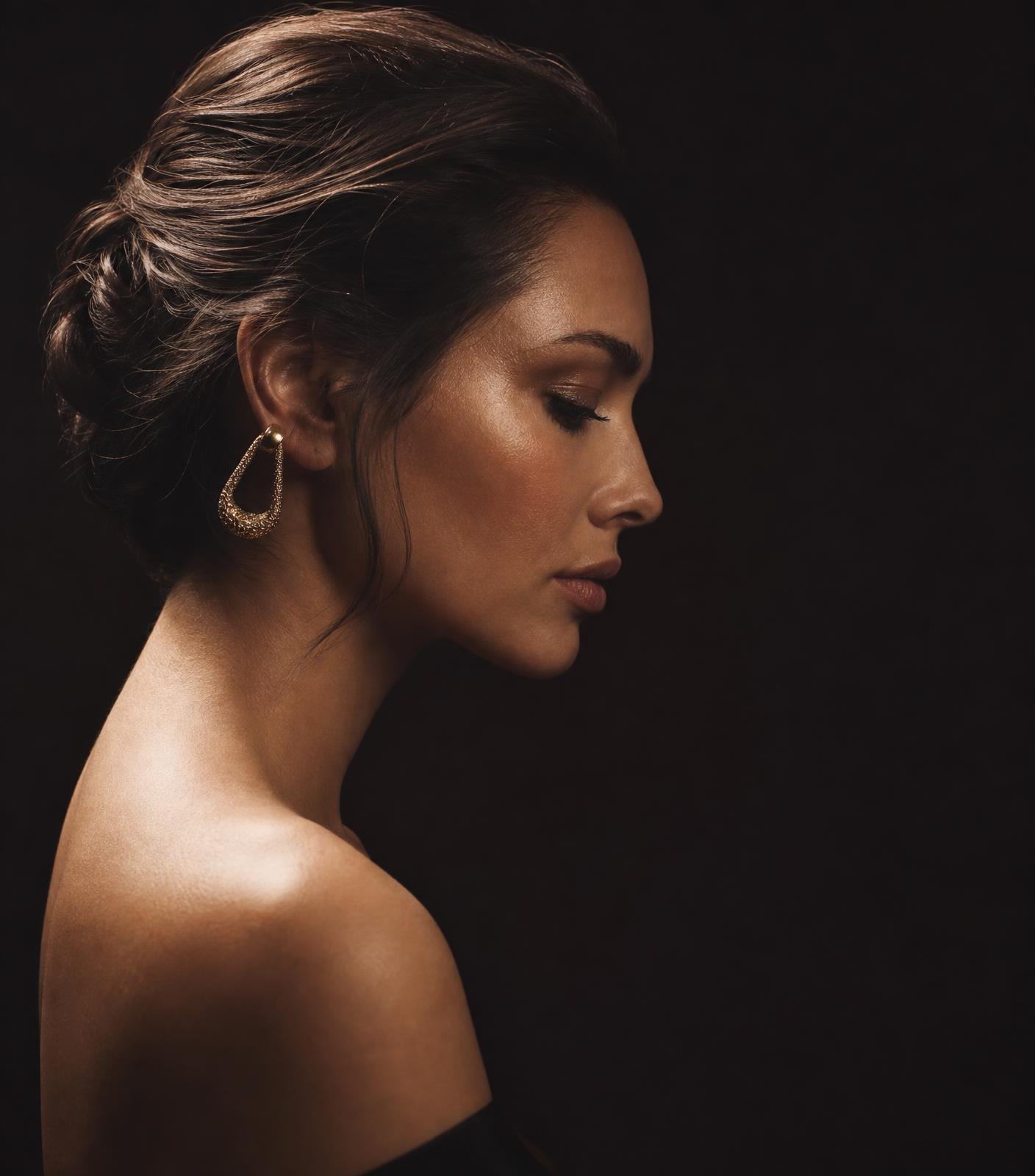 Dark editorial beauty portrait with sleek styled hair and champagne lighting